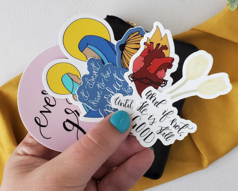 Hand holding a colorful sticker with text and design elements on a white background